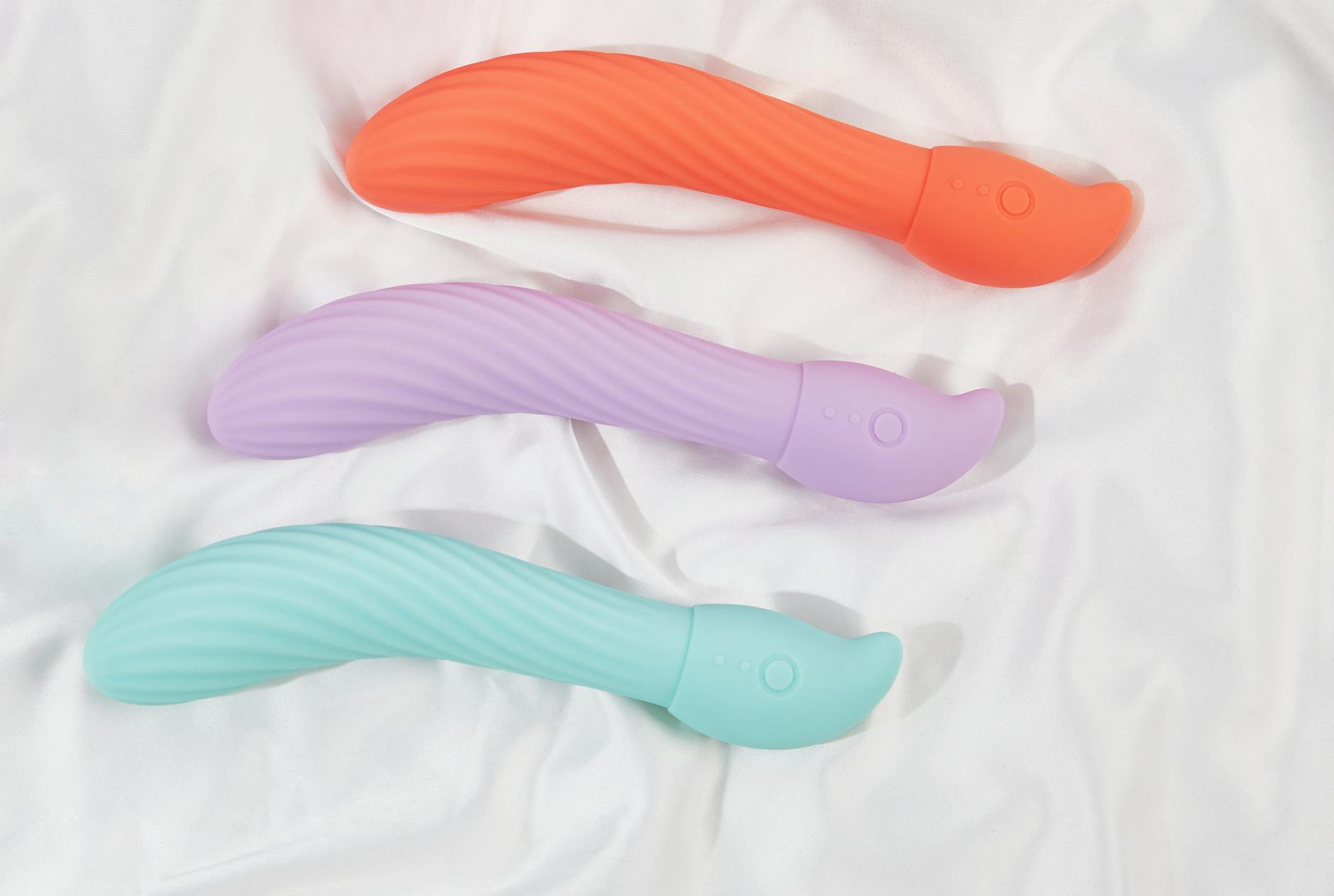Three colorful vibrators on white fabric, including a lemon-shaped toy highlighting texture and design