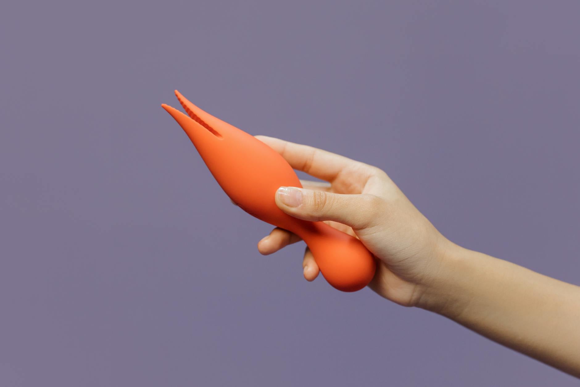 Hand holding a lemon clitoral vibrator against a purple background, showcasing solo pleasure and self-discovery