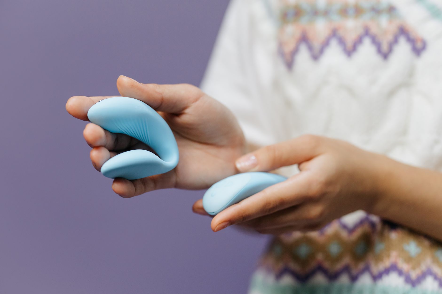 Woman holding a sleek blue lemon vibrator against a purple background, symbolizing reclaimed personal pleasure.