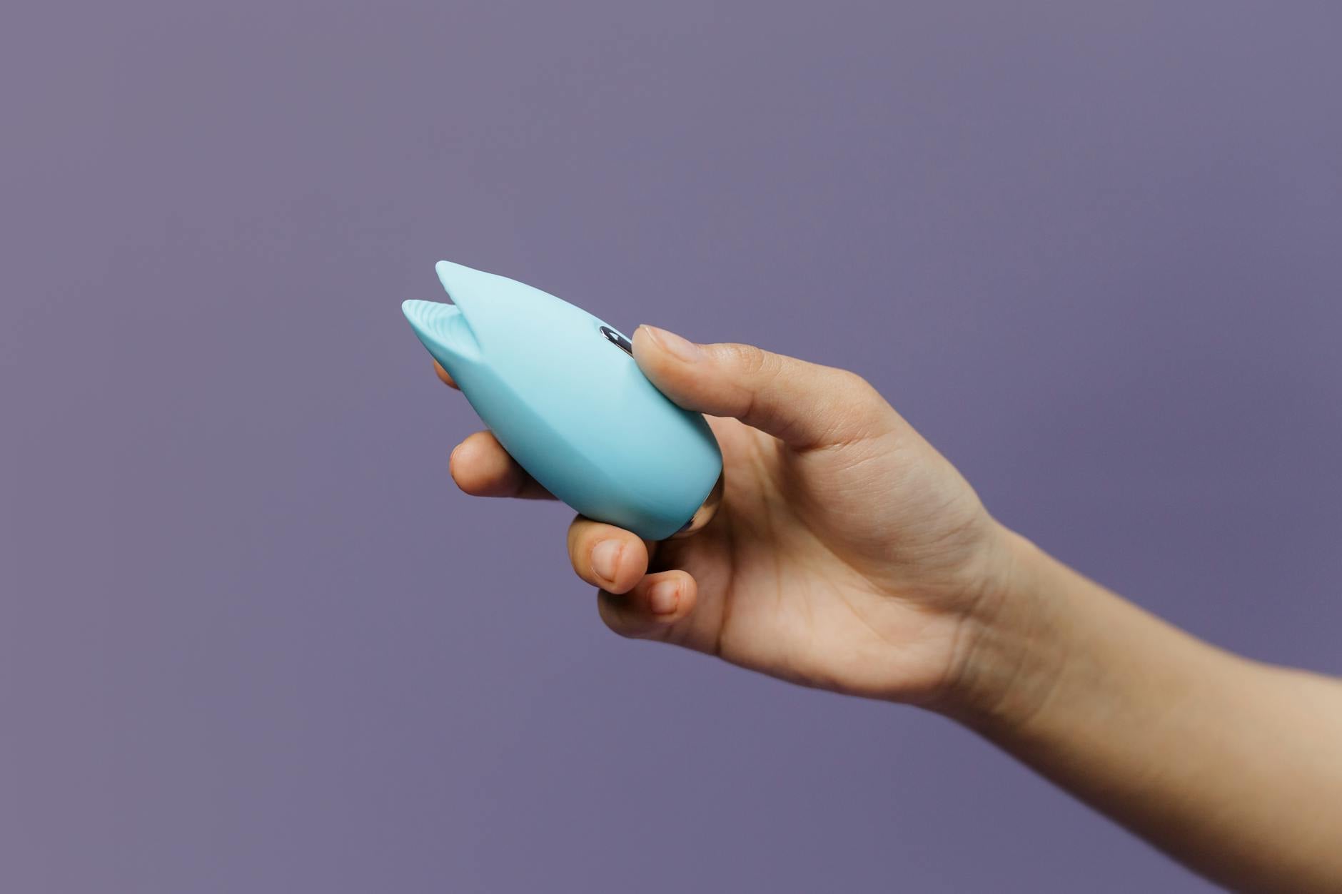A silicone lemon vibrator held in hand against a purple background, promoting self-love and mutual pleasure.