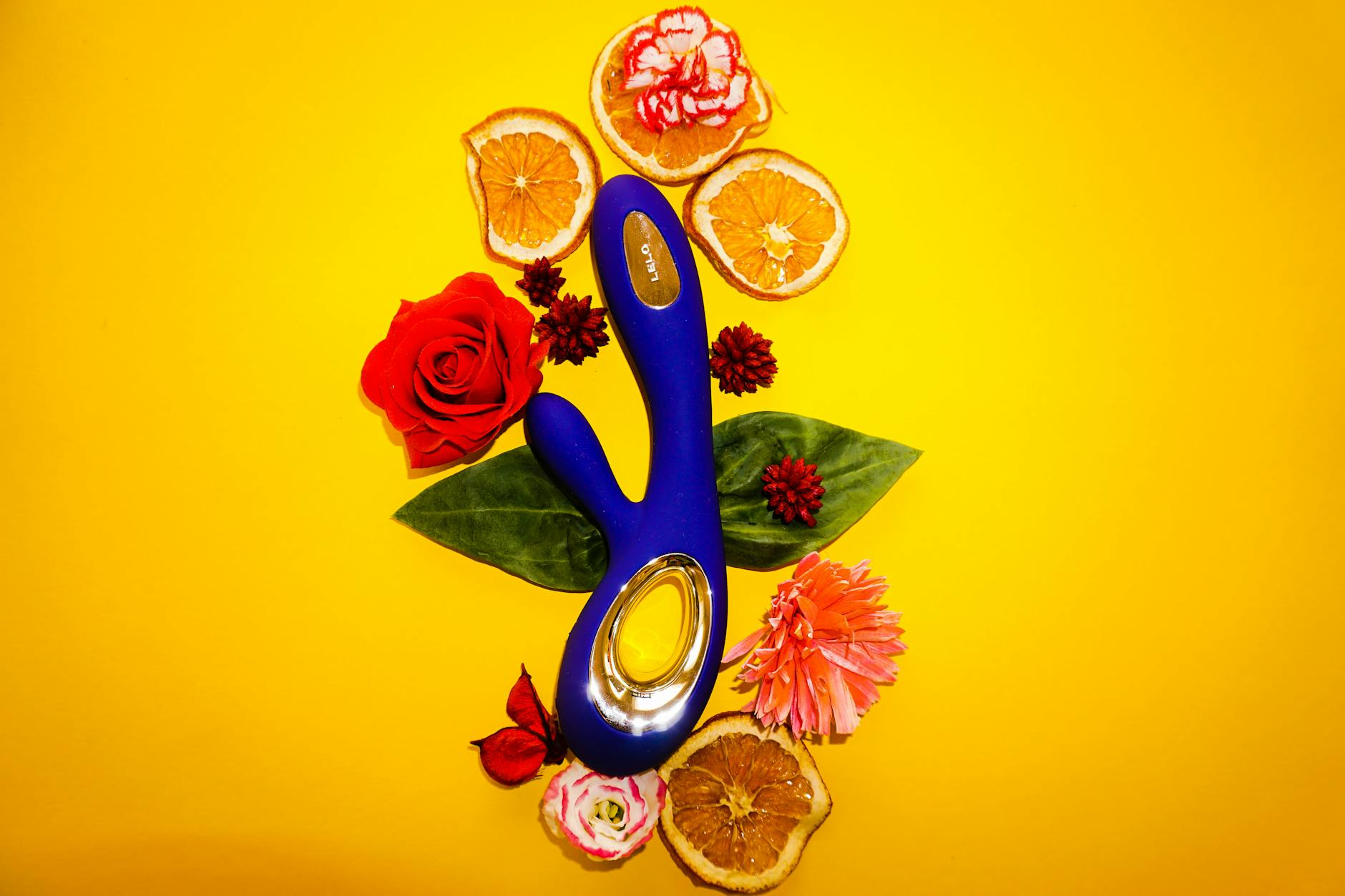 A hand holding an orange vibrator against a minimalistic purple backdrop, showcasing modern sensuality.