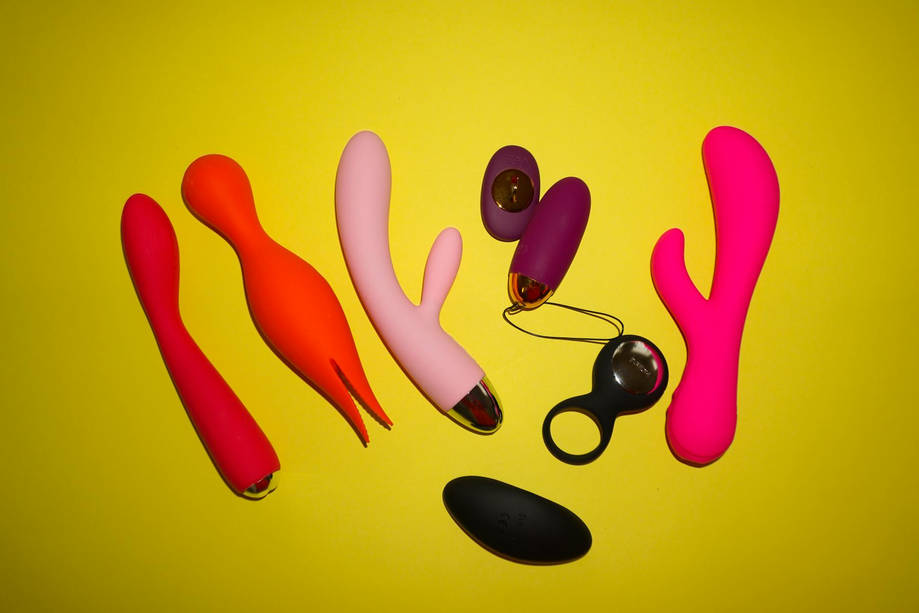 Colorful vibrators arranged on a bright yellow studio background