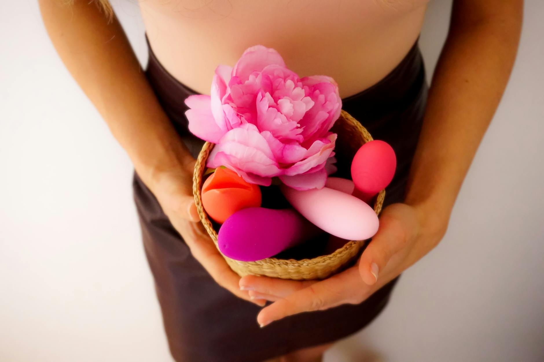 Close-up of a hand holding an orange vibrator against a minimalistic purple backdrop